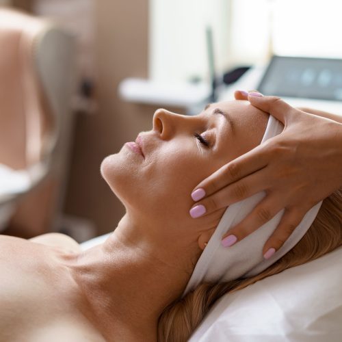Face massage. Close-up of adult woman getting spa massage treatment at beauty spa salon. Spa skin and body care. Facial beauty treatment. Cosmetology.